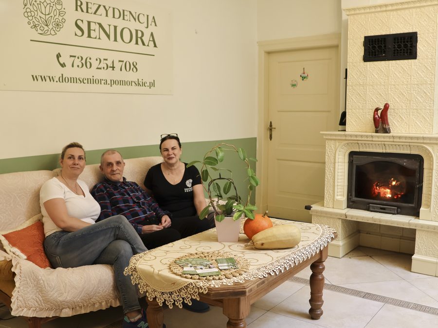 Salon wypoczynkowy z kominkiem i kanapą w Rezydencji Seniora