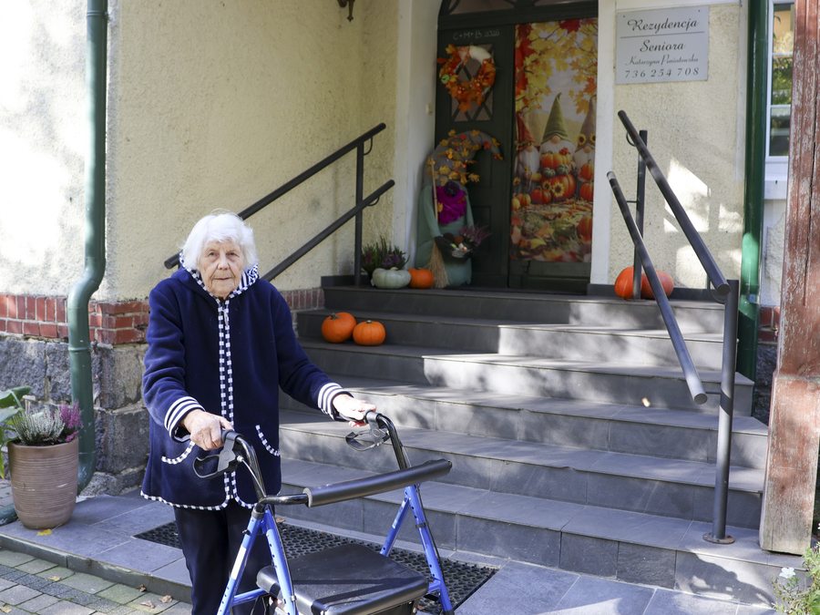 Seniorka z balkonikiem przed wejściem do Rezydencji Seniora