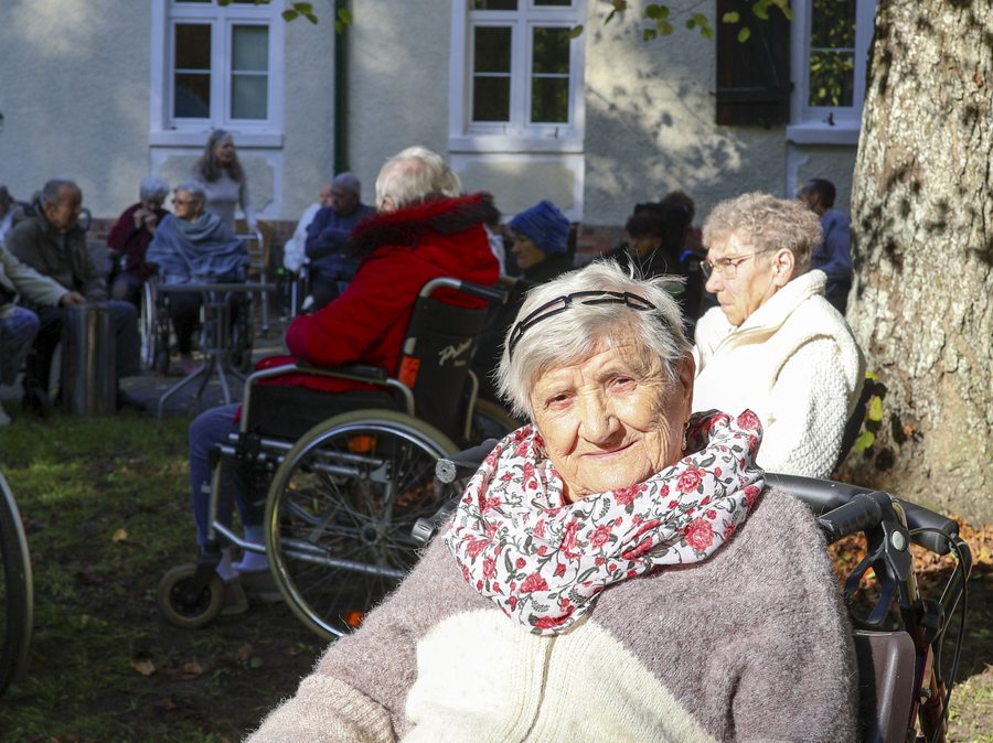 Seniorka na pierwszym planie podczas wspólnego pobytu w ogrodzie