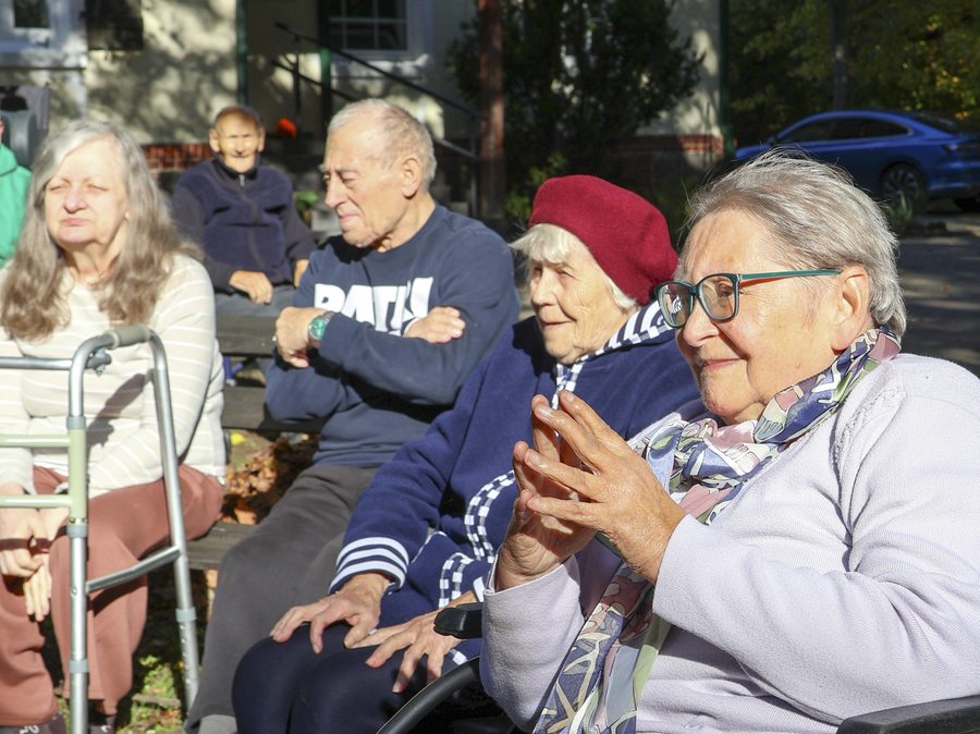Mieszkańcy i personel spędzają czas na ławkach w ogrodzie