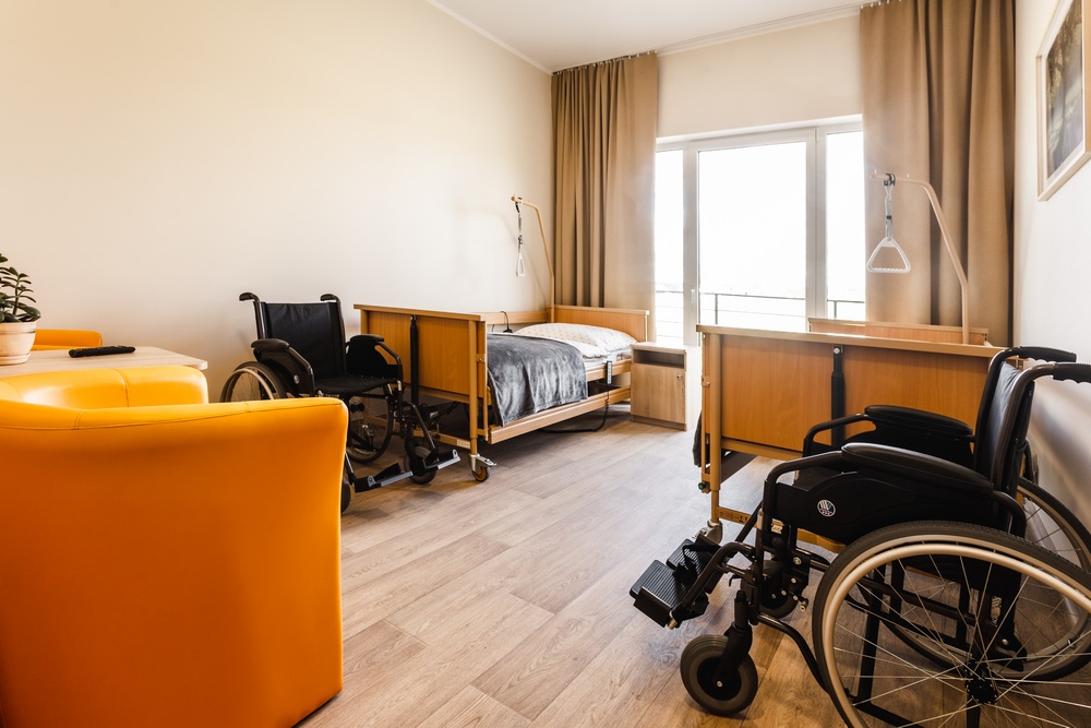 Pokój mieszkańca z łóżkami rehabilitacyjnymi i wyjściem na taras w Starej Maszynie